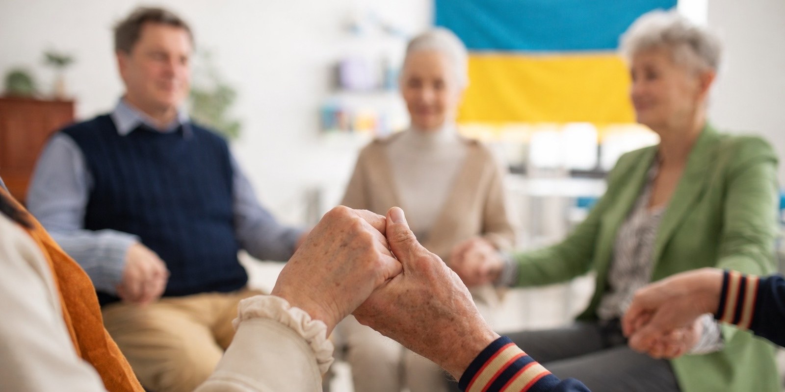 Menschen sitzen im Kreis und halten sich an den Händen